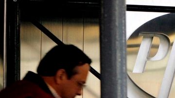 Un peatón  pasa junto al logo de la farmacéutica Pfizer Inc. en la sede de la compañía en Nueva York. La empresa fue sancionda por el gobierno.