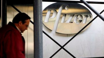 Un peatón  pasa junto al logo de la farmacéutica Pfizer Inc. en la sede de la compañía en Nueva York. La empresa fue sancionda por el gobierno.
