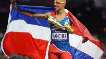 Félix Sánchez se envuelve en la bandera dominicana al ganar el lunes los 400 con vallas.