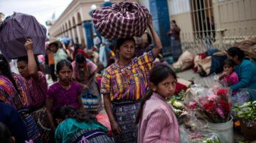 Una mujer indígena (c) camina con sus hijas en el mercado del pueblo de San Juan Sacatepéquez , día en que se celebra el Día Internacional de los Pueblos Indígenas.