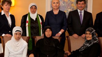 El ministro de Exteriores turco, Ahmet Davutoglu (d, de pie) y la secretaria de Estado de EEUU, Hillary Clinton, con refugiados sirios.