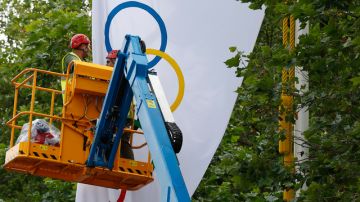 Trabajadores londinenses bajan una bandera con los aros olímpicos.