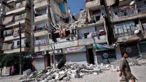 Un hombre camina frente a un edificio que quedó destruido tras los ataques que tuvieron lugar ayer en Alepo, Siria.