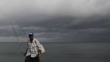 Un pescador se retira bajo un cielo nublado en la costa de Santo Domingo, República Dominicana, donde se espera el paso de la tormenta "Isaac".