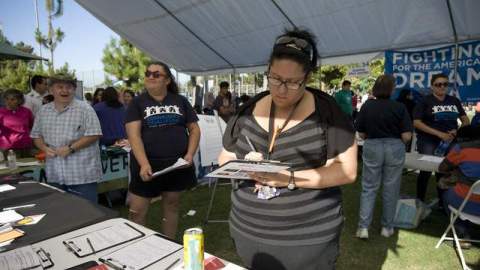 Amanda Ruiz (d) se registra con los representantes de Voto Latino en el Festival de Verano en el sur de Los Ángeles.