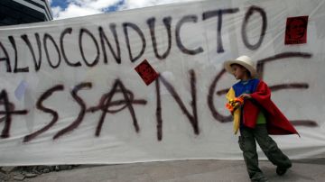 Un niño se coloca delante de una pancarta que dice en español "Salvoconducto para Assange" durante una manifestación en apoyo del asilo  del fundador de WikiLeaks.