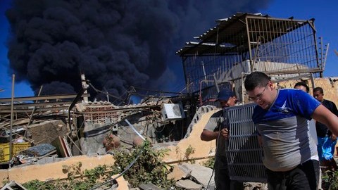 Los miembros de una familia llevan un aparato de aire acondicionado rescatado de su casa incendiada luego de una explosión en la refinería Amuay.
