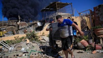 Los miembros de una familia llevan un aparato de aire acondicionado rescatado de su casa incendiada luego de una explosión en la refinería Amuay.