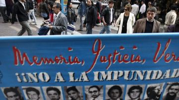 Varias personas observan carteles con las fotografías de desaparecidos ayer  durante el Día Internacional de las Víctimas de Desaparición Forzada, en Chile.