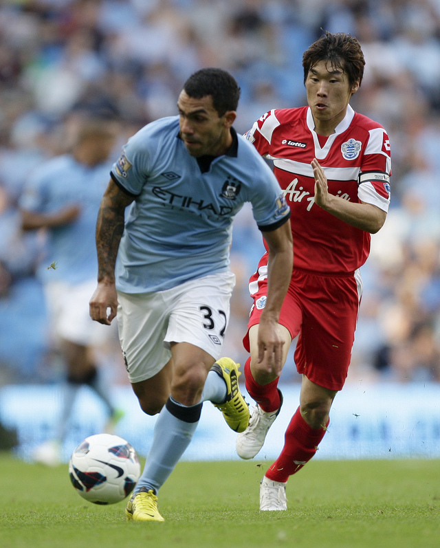 Carlos Tevez (izq), del Manchester City, controla el balón ante la marca de Park Ji-Sung, de Queens Park Rangers.