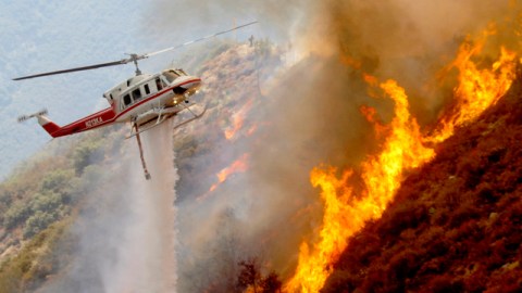 Helicópteros especiales de rescate lanzan agua y espuma para apagar las llamas del fuego forestal.