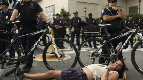 Un hombre se acuesta en el piso durante una protesta, mientras los policías custodian la inauguración de la convención del Partido Demócrata.
