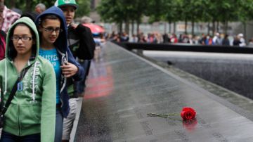 Visitantes al Monumento de Recordación del 9/11  pasan junto a una rosa colocada sobre el nombre de una de las víctimas.