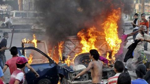 Manifestantes egipcios se reúnen alrededor de un vehículo en llamas en el centro de El Cairo, Egipto, antes que la policía despejara el área después de días de protestas en contra de una película que ridiculiza al profeta Mahoma.