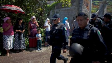 Policías federales caminanentre los habitantesde la población de  Nueva Jerusalen, en México.