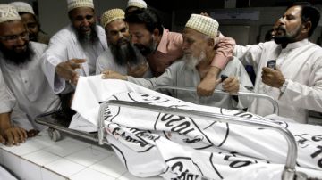 Paquistaníes lloran la muerte de una víctima de un atentado, en un hospital local ayer en Karachi, Pakistán, mientras las autoridades buscaban a los autores.