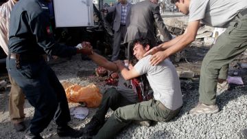 Los hermanos de  un conductor  de minibús afgano que murió  en un atentado suicida lloran  en la escena del hecho, ayer en Kabul,    Afganistán.