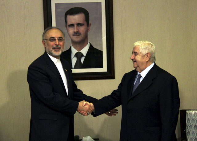 El ministro sirio de Exteriores, Walid al Moallem (dcha), estrecha la mano de su homólogo iraní, Ali Akbar Salehi, en Damasco (Siria).