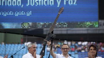 El presidente  Otto Pérez Molina (i), y la vicepresidenta, Roxana Baldetti (d), aplauden al músico colombiano César López (c), quien sostiene una "Escopetarra", combinación de una escopeta y guitarra,  durante el concierto.