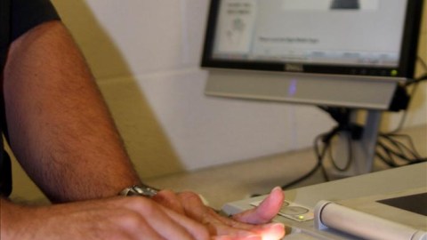 Un agente procesa a un detenido hispano sin identificar en el marco del programa migratorio Comunidades Seguras.