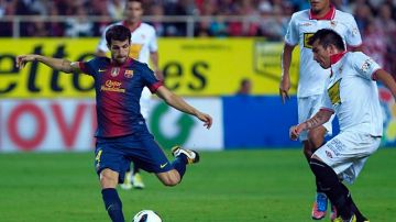Cesc Fàbregas (i) dispara para marcar el primer gol del Barcelona ante la presión del chileno Gary Medel, volante del Sevilla que al final cayó en su estadio, el Sánchez Pizjuán.