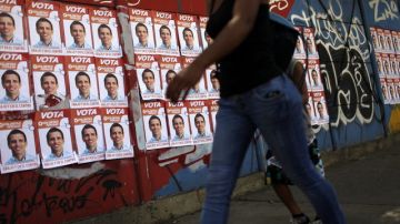 Una mujer camina frente a una pared con publicidad electoral del candidato Henrique Capriles Radonski en el centro de Caracas (Venezuela).