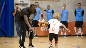 Ussain Bolt juega baloncesto con un niño durante su vista a Neva Zelanda.