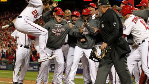 Los jugadores de los Nacionales esperan en la goma a  Jayson Werth (izq.) quien salta luego de pegar el jonrón de la victoria.