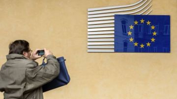 Tras conocerse la noticia hoy, un turista saca una foto de la bandera europea en los cuarteles de la Unión Europea en Bruselas.