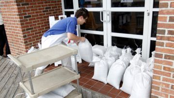 La empleada de un restaurante de Ocean City en Maryland, coloca bolsas de arena a la entrada del negocio para evitar que el agua inunde lugar.