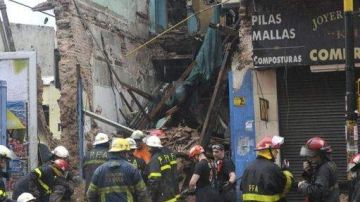 Bomberos remueven escombros de un local que se derrumbó esta mañana en un barrio de Buenos Aires, debido a las fuertes lluvias.