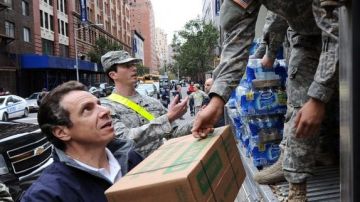 El gobernador de Nueva York, Andrew Cuomo, ayuda a unos soldados de la Guardia Nacional mientras distribuyen en varios camiones cajas con alimentos.
