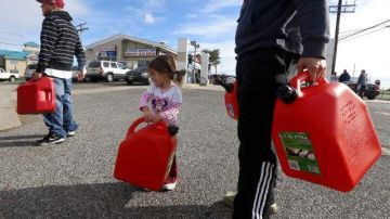 Una pequeña ayuda a su padre en una fila para obtener gasolina en una ciudad de Nueva Jersey, donde aun no hay electricidad, después del paso de la tormenta.