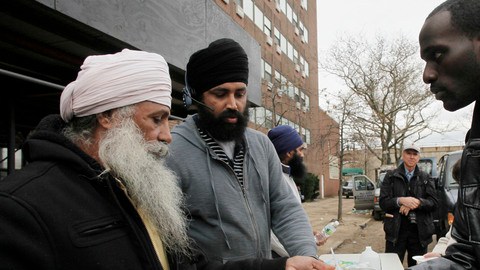Singh Tarlok (izq.) sirve un plato de comida a Arnell Franklin durante una línea de solidaridad establecida por voluntarios comunitarios en Far Rockaway, Queens, un área devastada por  Sandy.