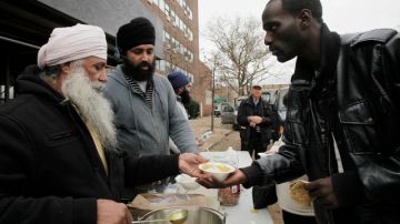 Singh Tarlok (izq.) sirve un plato de comida a Arnell Franklin durante una línea de solidaridad establecida por voluntarios comunitarios en Far Rockaway, Queens, un área devastada por  Sandy.