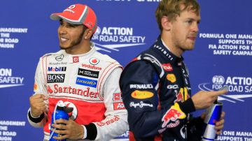 El británico Lewis Hamilton (izq), piloto de McLaren Mercedes, celebra tras ganar la pole al alemán Sebastian Vettel (d), del equipo Red Bull, para la carrera de hoy.