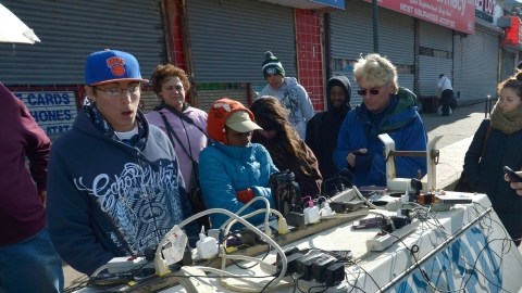 Personas, incluso bajo el intenso frío,  cargan sus celulares en un generador de la policía en la zona  de Rockaways, de la famosa barriada de Queens, en Nueva York.
