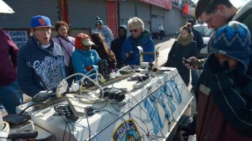 Personas, incluso bajo el intenso frío,  cargan sus celulares en un generador de la policía en la zona  de Rockaways, de la famosa barriada de Queens, en Nueva York.