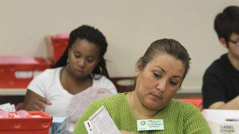 Cynthia Salinas, centro, procesa una boleta enviada por correo en el Registro del Condado de Sacramento de Votantes en Sacramento, California.
