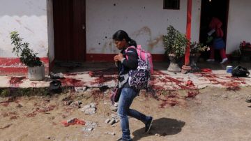 Una mujer camina frente a la casa donde presuntos sicarios asesinaron a diez integrantes de una familia en Santa Rosa, Colombia.
