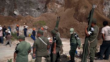 Soldados y trabajadores de rescate buscan a las víctimas en un sitio de extracción de arena después de un terremoto.