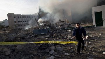 Un oficial palestino precinta una zona después de un ataque aéreo en Gaza.