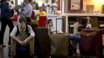 Turistas sentados en su equipaje esperando que les cambien sus vuelos en el aeropuerto de Buenos Aires, Argentina.