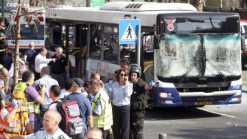 Policías y miembros de los equipos de rescate revisan el lugar donde explotó un bus en una zona de Tel Aviv.