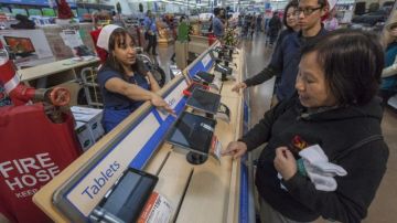 Danae Salcedo (i), trabajdora de Walmart atiende a unos clientes con los Tablets en Rosemead, California.