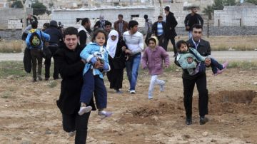 Varios sirios huyen de su país tras los enfrentamientos entre las tropas gubernamentales y los rebeldes en la región de Rasulayn, a unos cientos de metros del pueblo turco de Ceylanpinar.