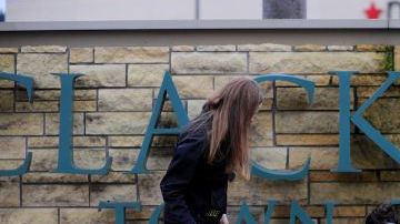 Dos personas colocan flores en homenaje a las víctimas del tiroteo en el centro comercial Clackamas Town Center, en un suburbio de Portland, Oregon.
