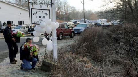 Ciudadanos llegan al exterior de la escuela para dejar flores en un pequeño altar que se levantó para recordar a las víctimas del atentado.