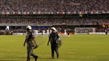 Oficiales de policía abandonan el campo de juego mientras los jugadores del Sao Paulo esperaban el regreso de los integrantes de Tigre, que perdía 2-0 al final del primer tiempo de la final de la Copa Sudamericana.