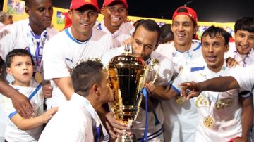 Los jugadores del Olimpia exhiben orgullosos  el trofeo que los acredita como tricampeones   del futbol profesional de Honduras.